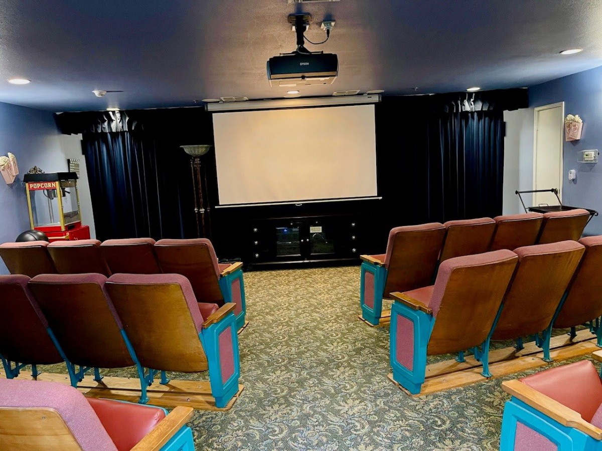 A cozy home theater setup with rows of seating facing a large screen and projector.
