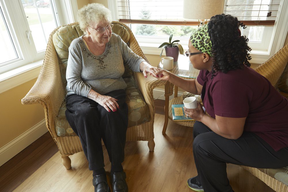 A caregiver assisting an elderly person in a comfortable home setting.