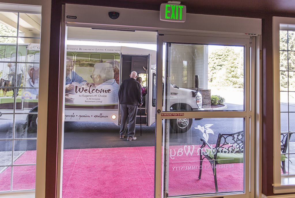 A coffee truck parked outside a restaurant entrance with a red carpet, as seen through open doors.