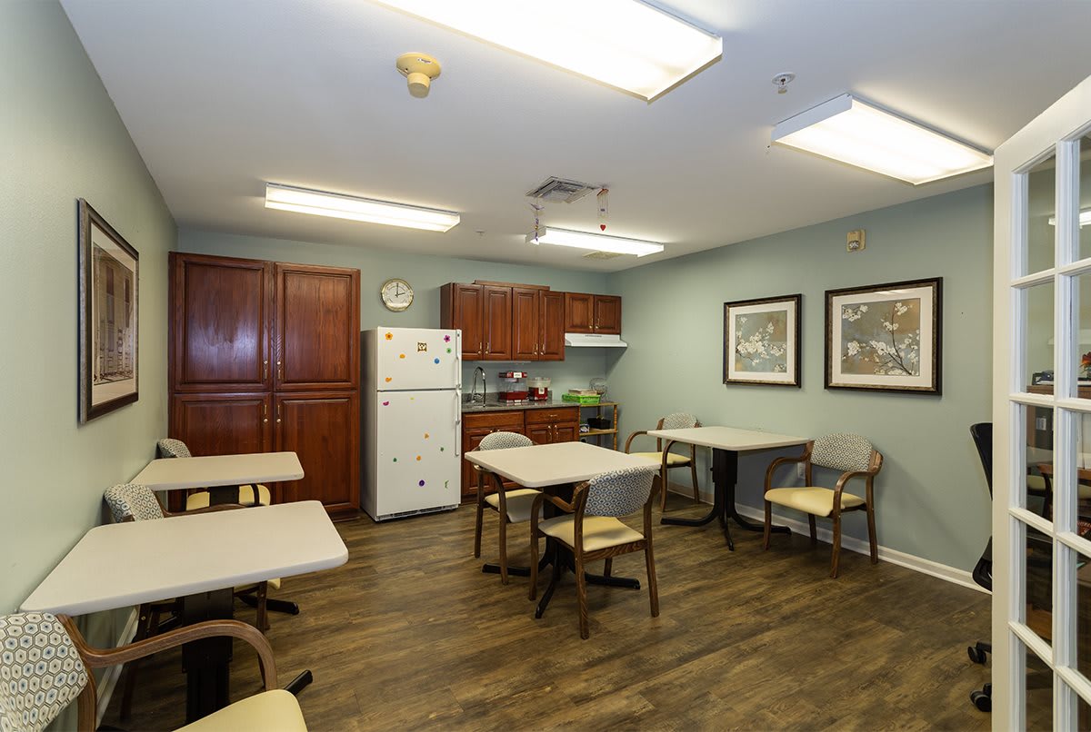 A communal kitchen and dining area with tables, chairs, and kitchen appliances.