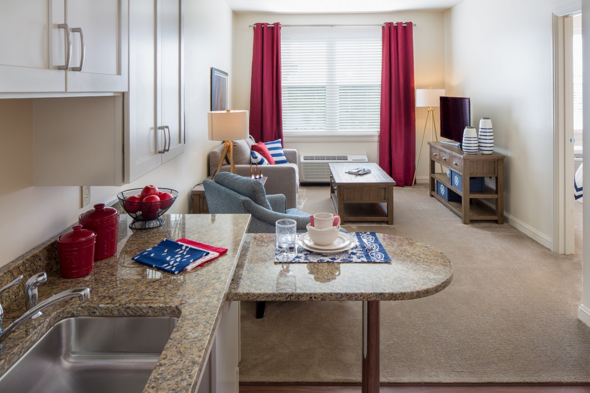 A modern open-plan living space featuring a cozy living room with red curtains and a kitchen area.