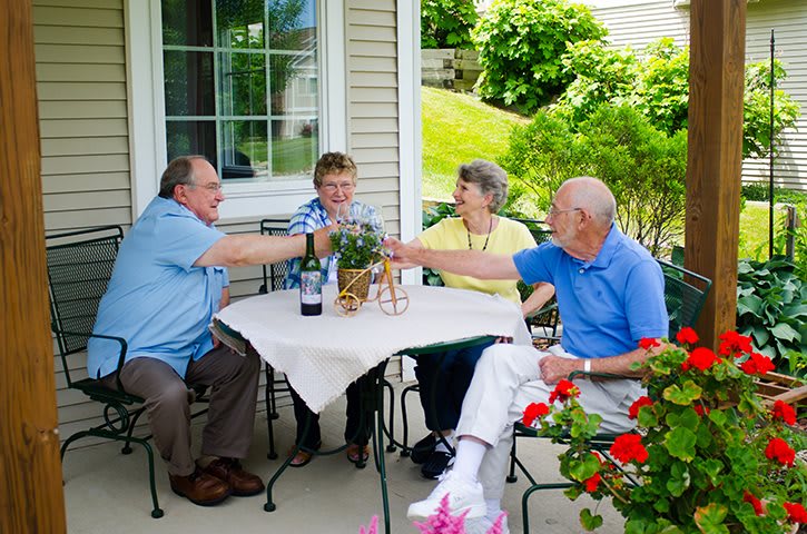 A group of seniors enjoying a social gathering on a patio, raising glasses in celebration.