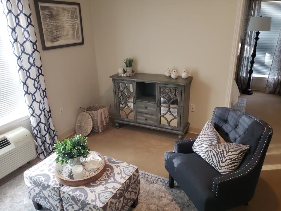 A cozy living room corner featuring a mirrored cabinet, an armchair with patterned cushions, and a decorated coffee table.