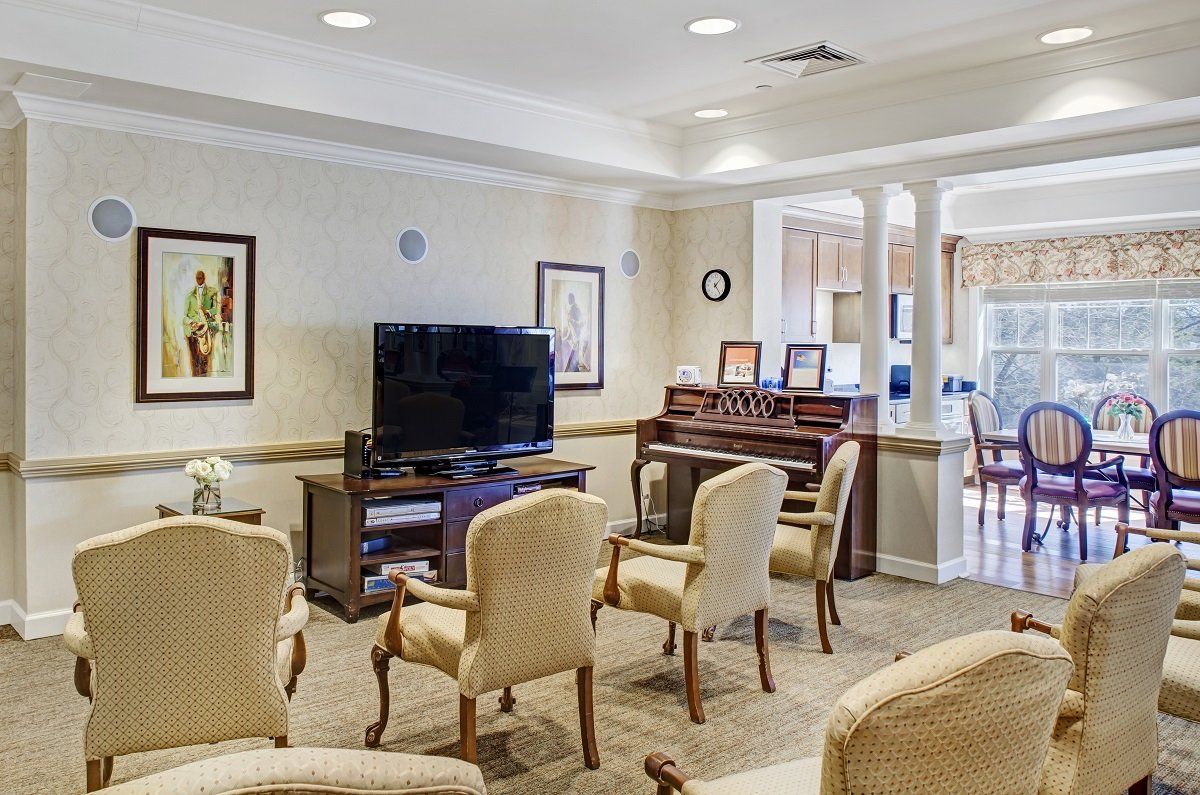 A cozy living room with comfortable chairs, a television, and framed artwork on the walls.