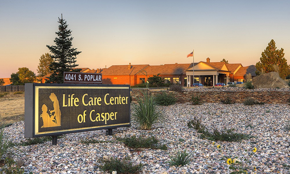 A scenic view of the Life Care Center of Casper at sunset with a visible sign and landscaped surroundings.