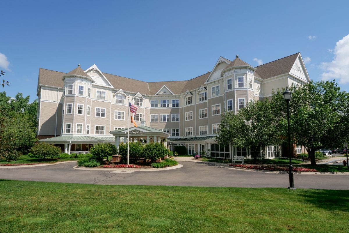 A large, multi-story residential or hotel building with a manicured lawn and clear blue sky.