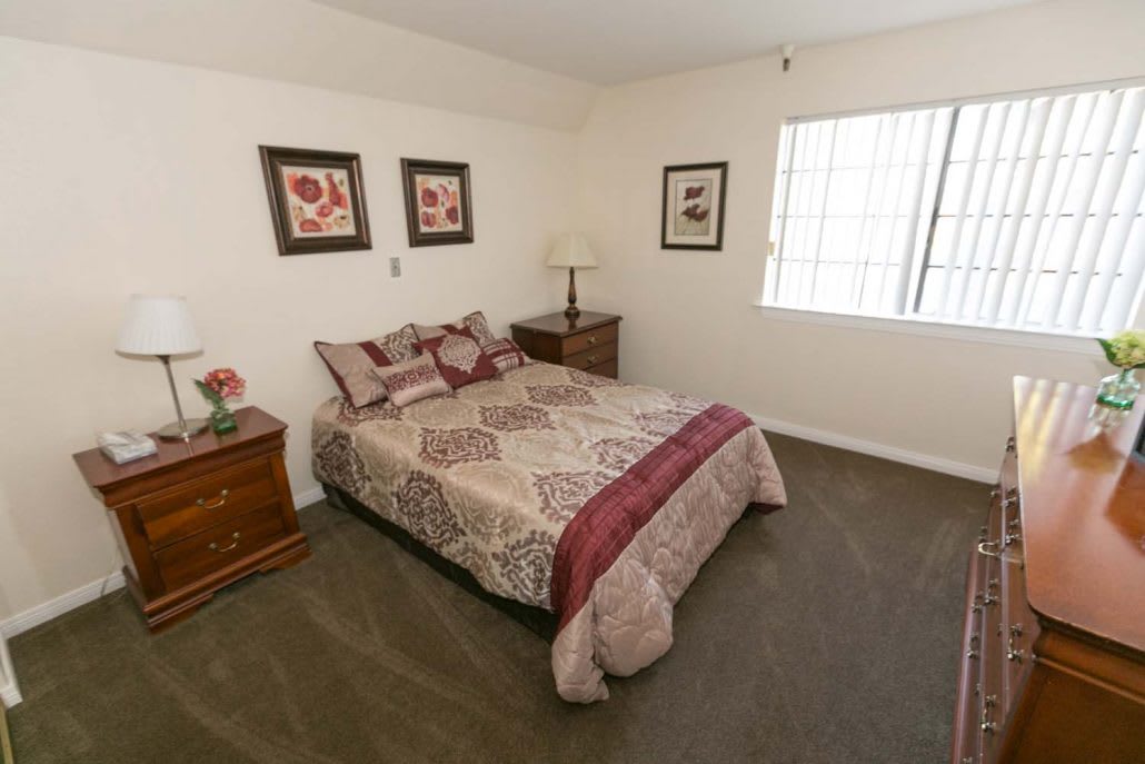 A cozy bedroom with a neatly made bed, nightstands, and framed artwork on the walls.