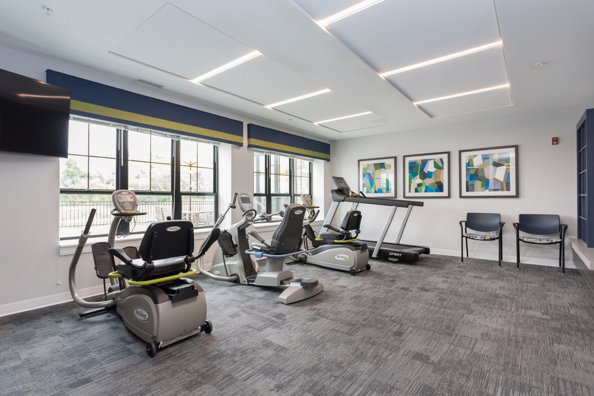A modern gym with various exercise equipment and large windows.
