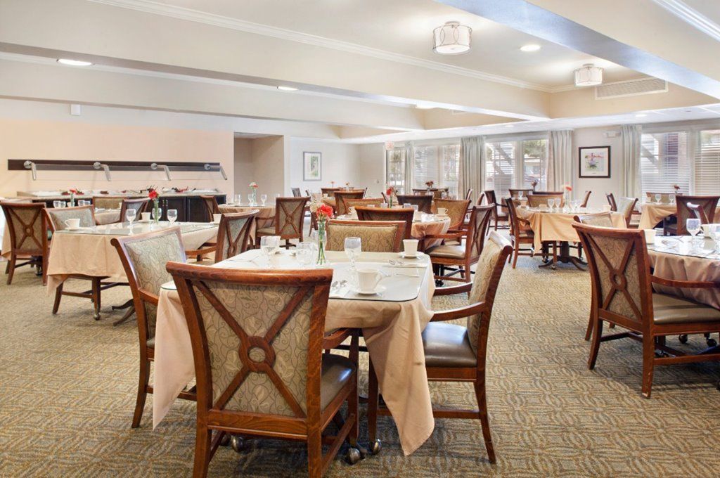 An elegant dining room with neatly arranged tables and chairs in a warm, neutral color palette.