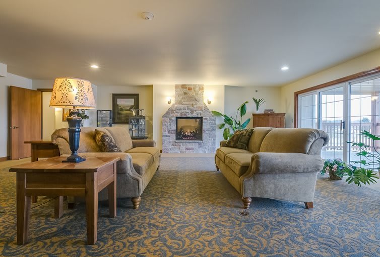 A cozy living room featuring a stone fireplace, two plush sofas, and warm lighting.
