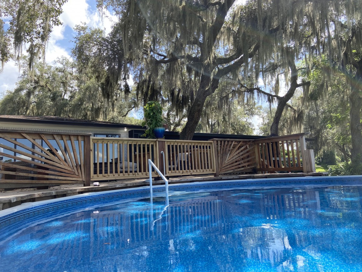 A serene outdoor pool surrounded by a wooden deck and lush trees.