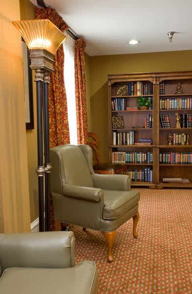 A cozy reading room with a comfortable armchair and a well-stocked bookshelf.