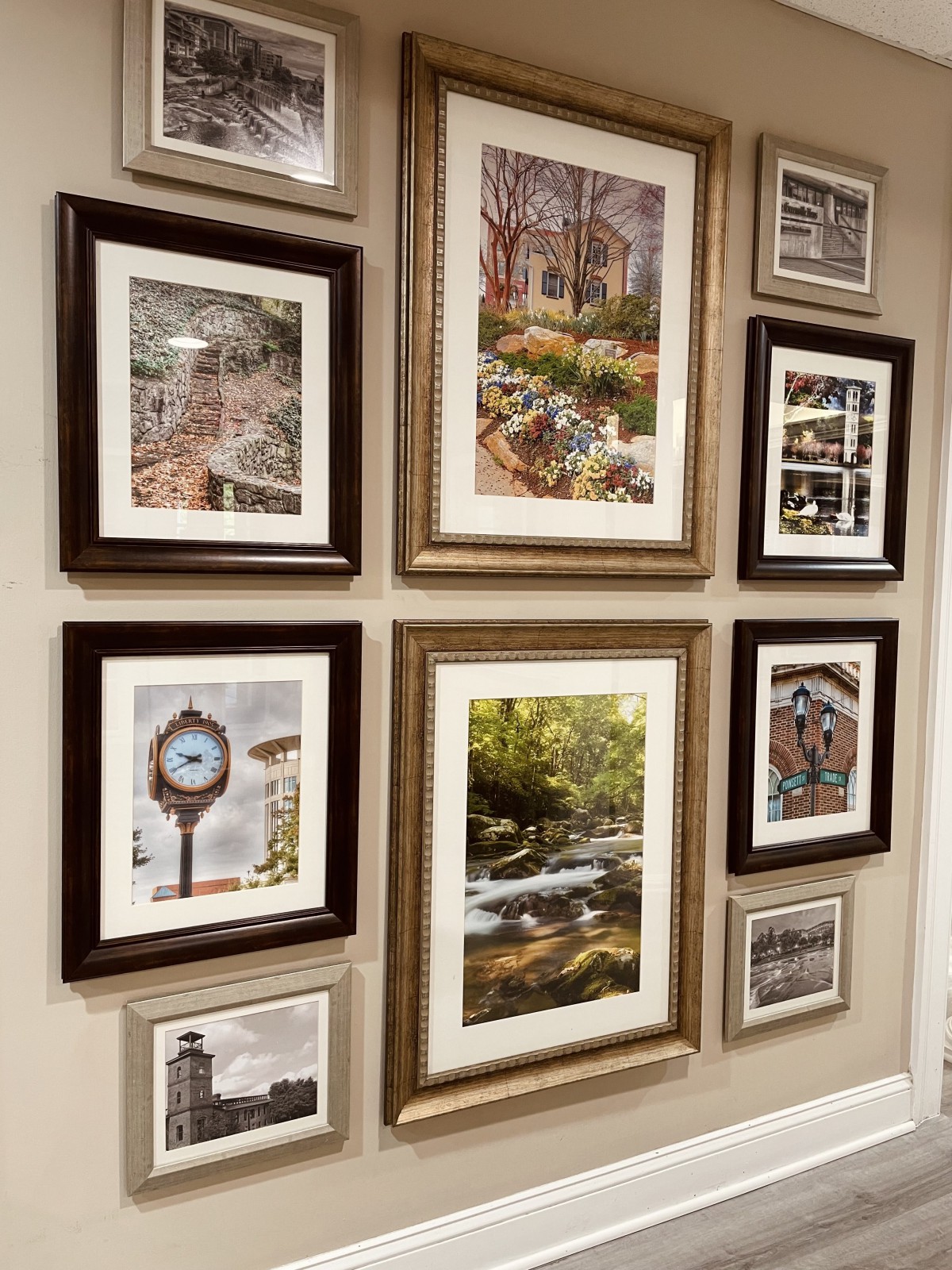 A collection of framed artworks displayed on a wall in an art gallery setting.