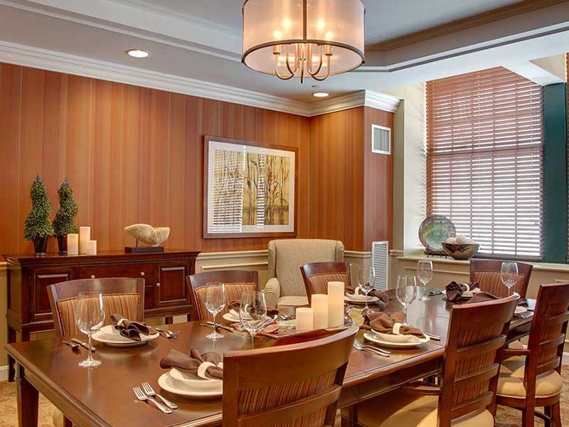 A modern dining room with elegant table settings and warm wood paneling.