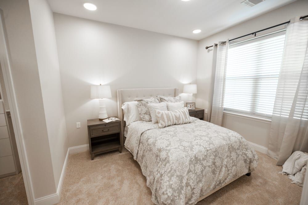 A cozy and well-decorated bedroom with a neatly made bed, nightstands, and lamps.