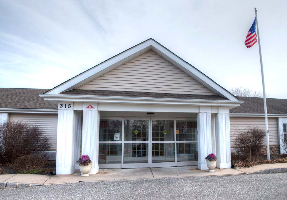 Front view of a building entrance with columns and glass doors.