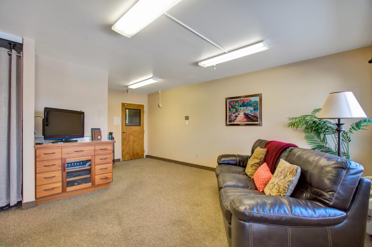 A cozy living room with a leather sofa, television, and artwork on the wall.