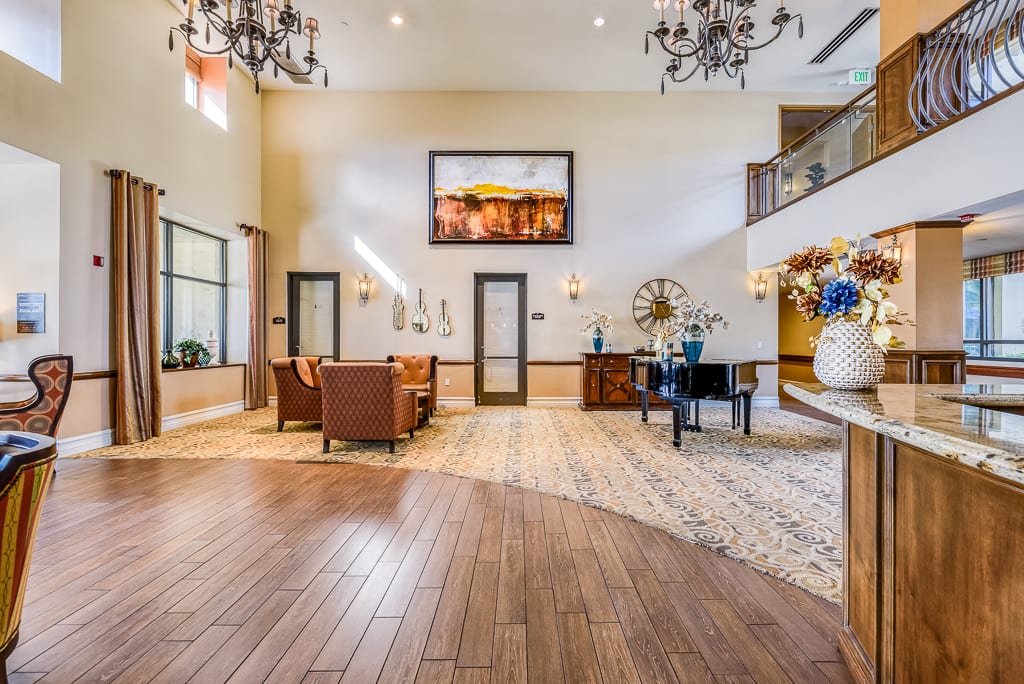 A spacious lobby with elegant decor, featuring wood flooring, chandeliers, and comfortable seating.