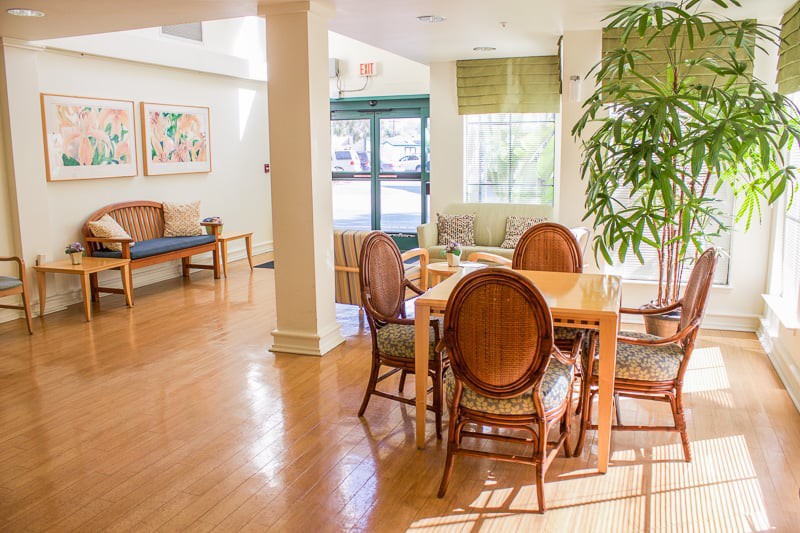 A cozy living room featuring a wooden dining table, elegant chairs, and abundant natural light.