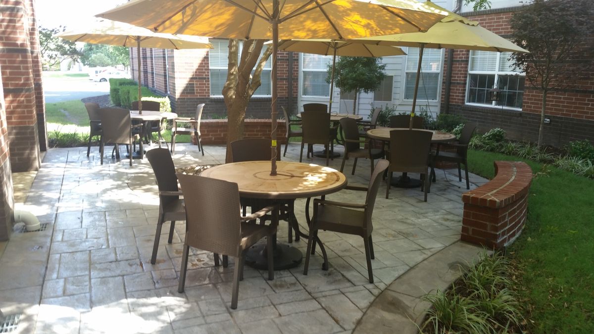 A peaceful outdoor patio area with tables, chairs, and umbrellas on a sunny day.
