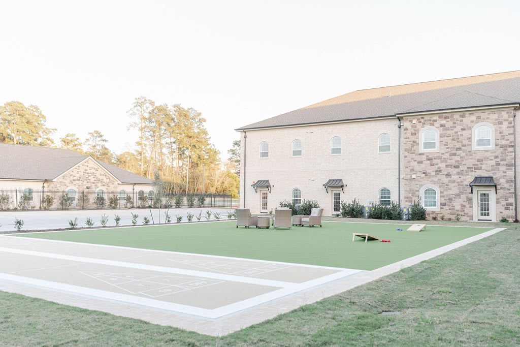 A spacious backyard features a well-maintained lawn and outdoor furniture, adjacent to a large building.