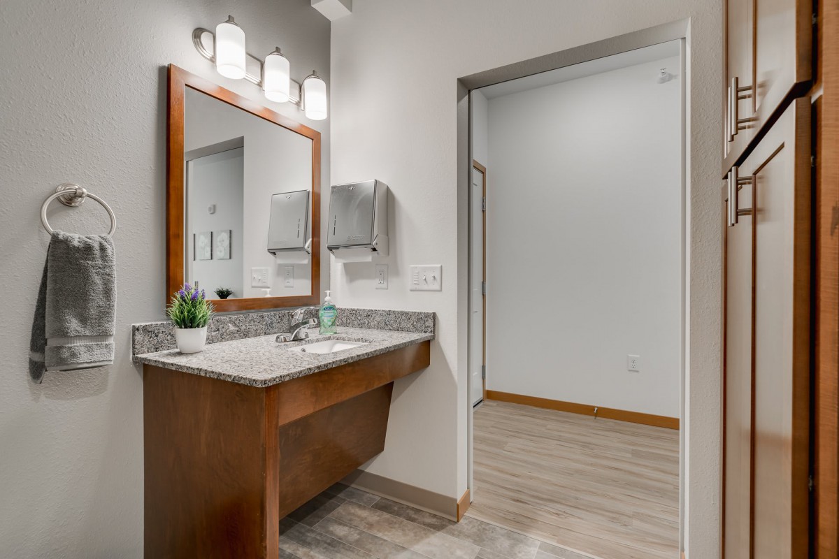 A modern bathroom with a single sink, large mirror, and wood accents.