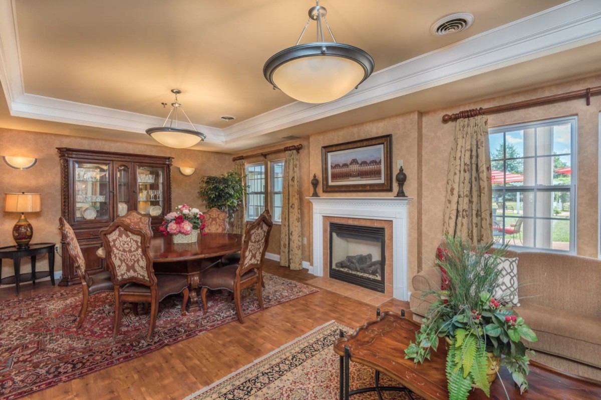 A beautifully furnished dining room with elegant chandeliers, a fireplace, and decorative artwork on the wall.
