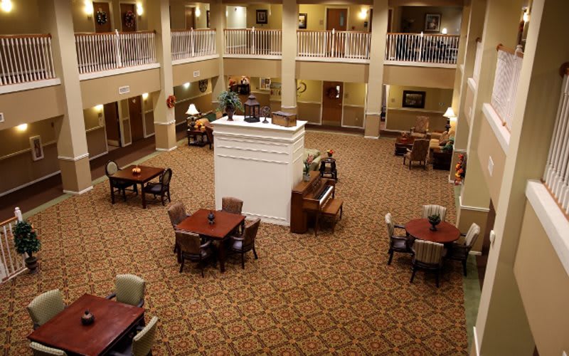 A spacious lobby with elegant furniture, featuring a grand piano and multiple seating areas.