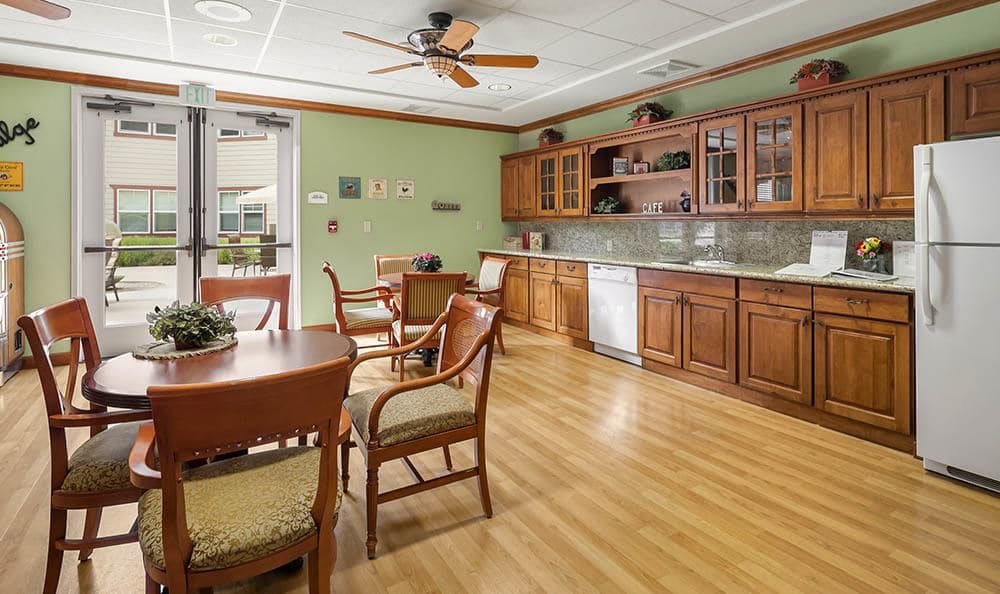 A cozy kitchen and dining area featuring wooden cabinets and furniture, with a ceiling fan and hardwood flooring.