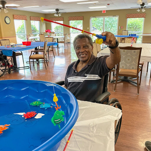 A joyful moment at a community center, where an individual in a wheelchair enjoys playing a fishing game.