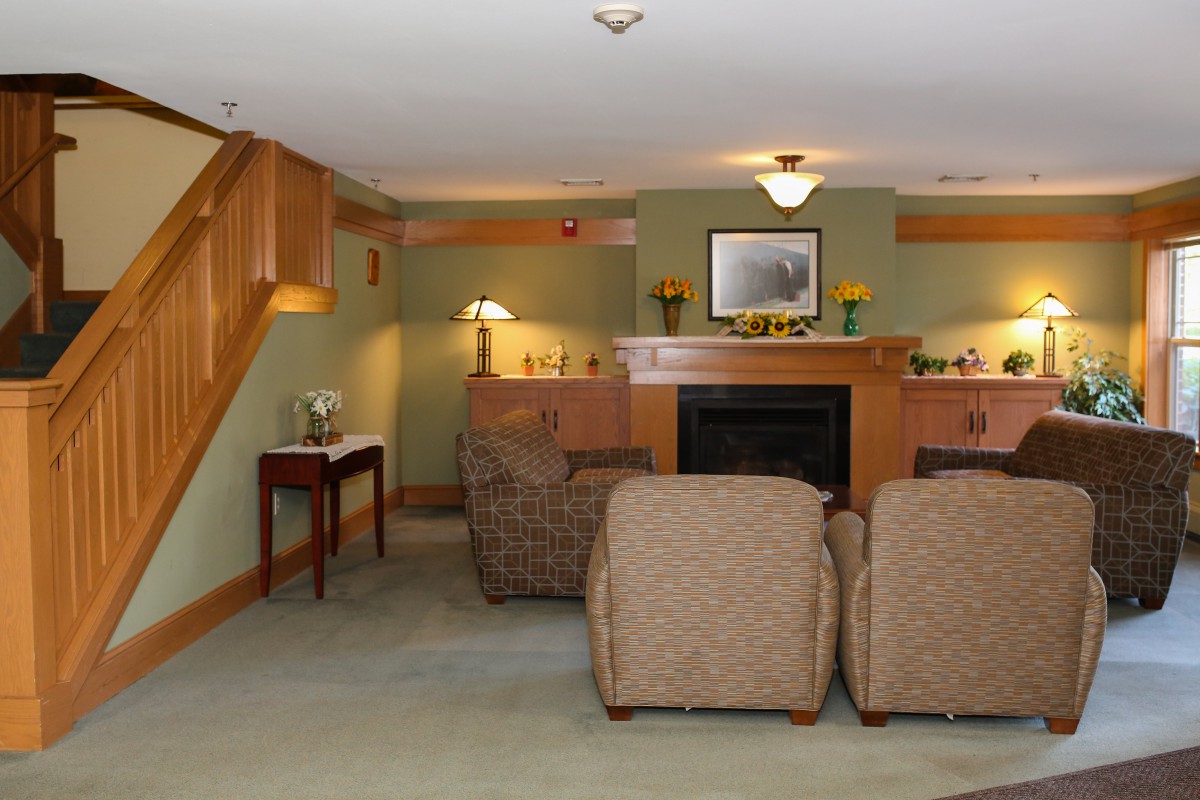 A cozy living room featuring a fireplace, comfortable seating, and warm wooden accents.