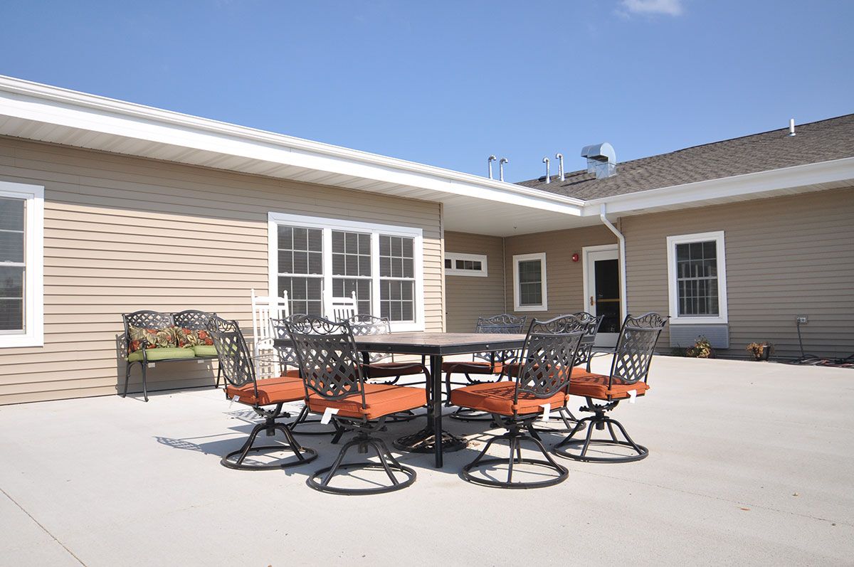 A sunny outdoor patio with a table and chairs in front of a building.