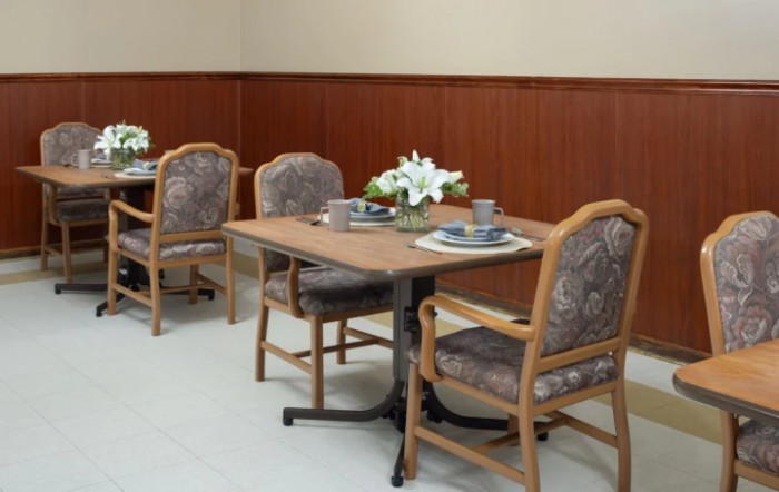 A cozy dining area with tables and chairs, featuring a floral centerpiece.