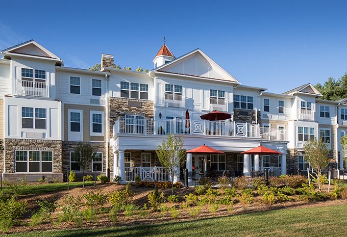 A large residential building with landscaped gardens and multiple windows under a clear blue sky.