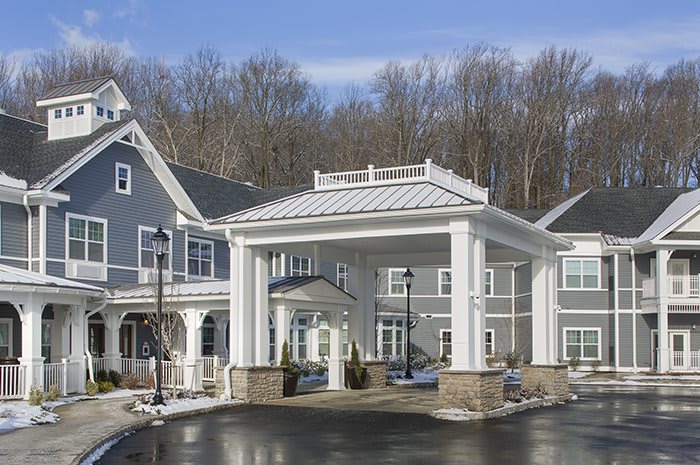 A residential building with a covered entrance and snowy surroundings.