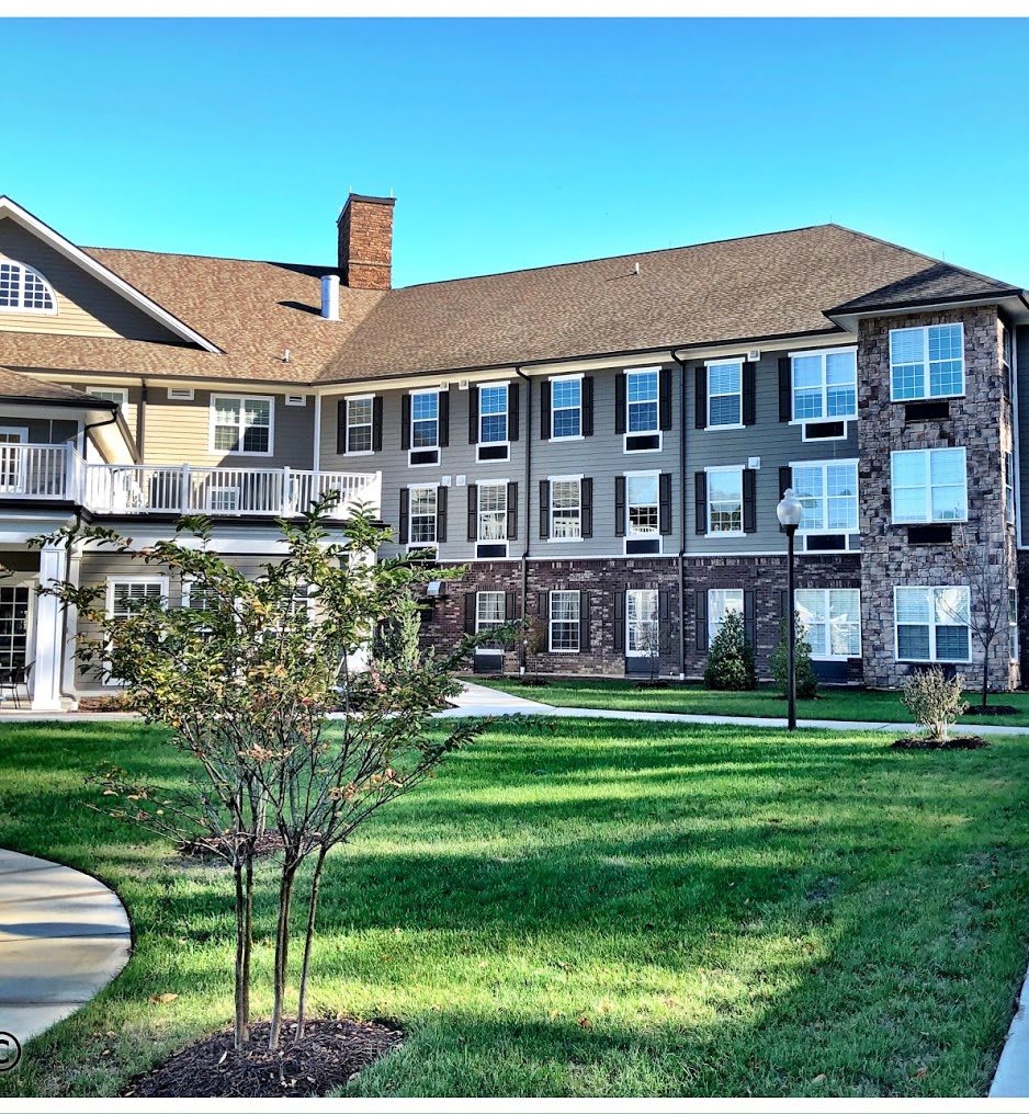 A residential building with a well-maintained lawn and trees in the foreground.