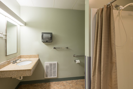A spacious bathroom featuring a shower, sink, and accessible facilities.