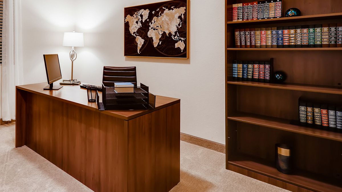A neat office space featuring a wooden desk, bookshelf, and a world map on the wall.