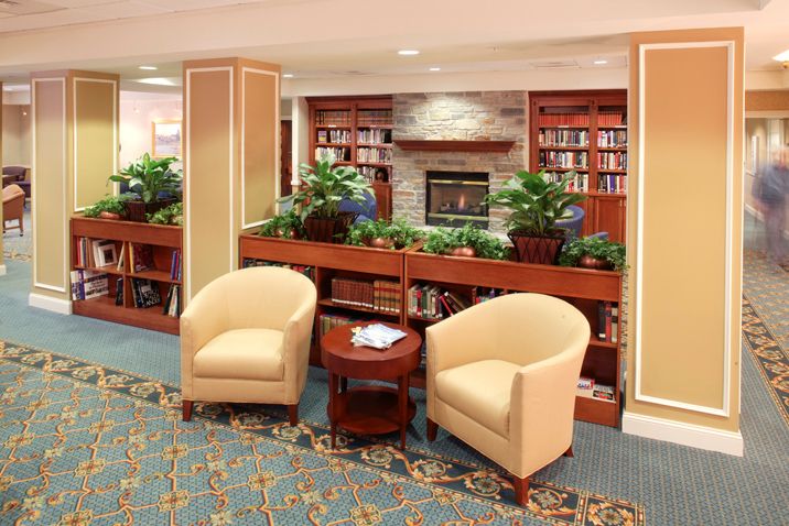 A cozy library lounge with plush seating, bookshelves, and a fireplace.