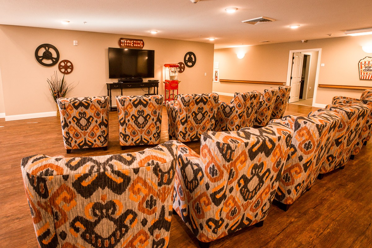 A cozy home theater setup featuring patterned armchairs and a large television.