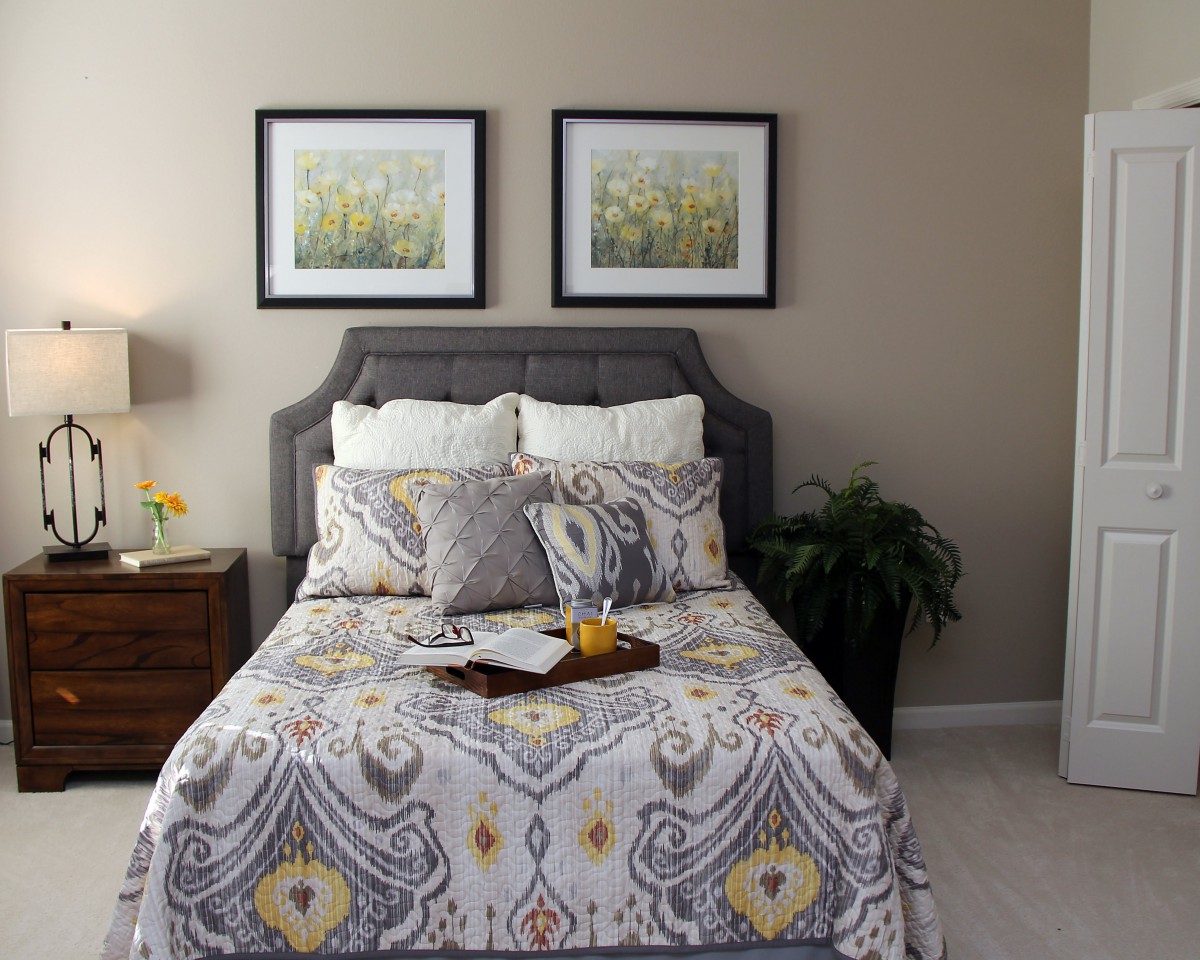 A cozy bedroom featuring a patterned comforter and two framed artworks above the bed.