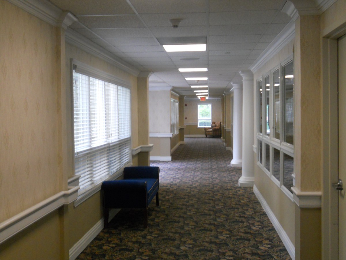 A long, carpeted hallway with windows and seating along the sides.