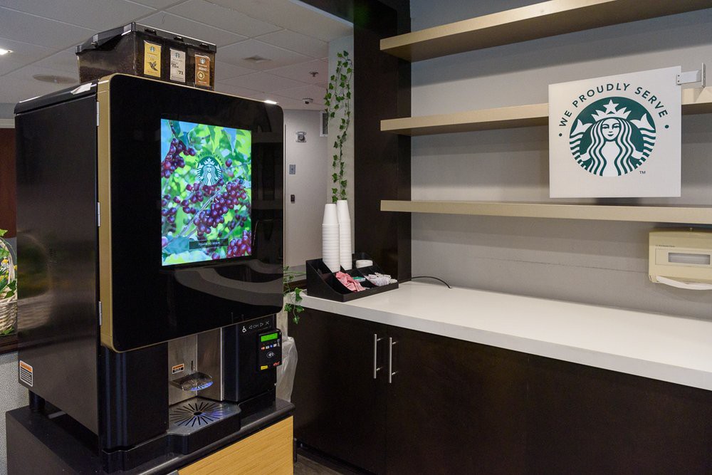 A modern coffee station with a coffee machine and empty shelves.