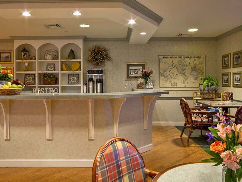 A cozy cafe interior featuring a counter, seating area, and warm lighting.