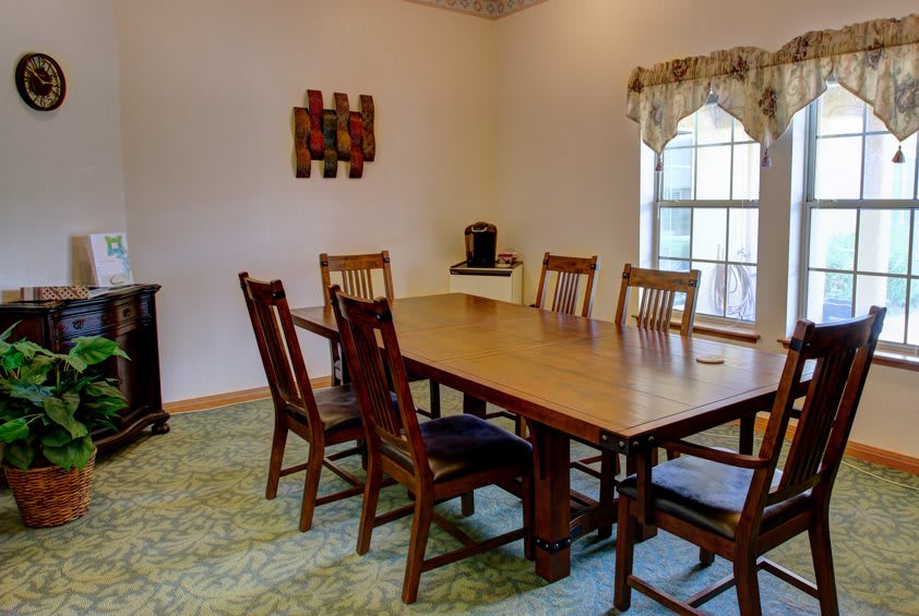 A cozy dining room with a wooden table and chairs, featuring a large window and decorative elements.