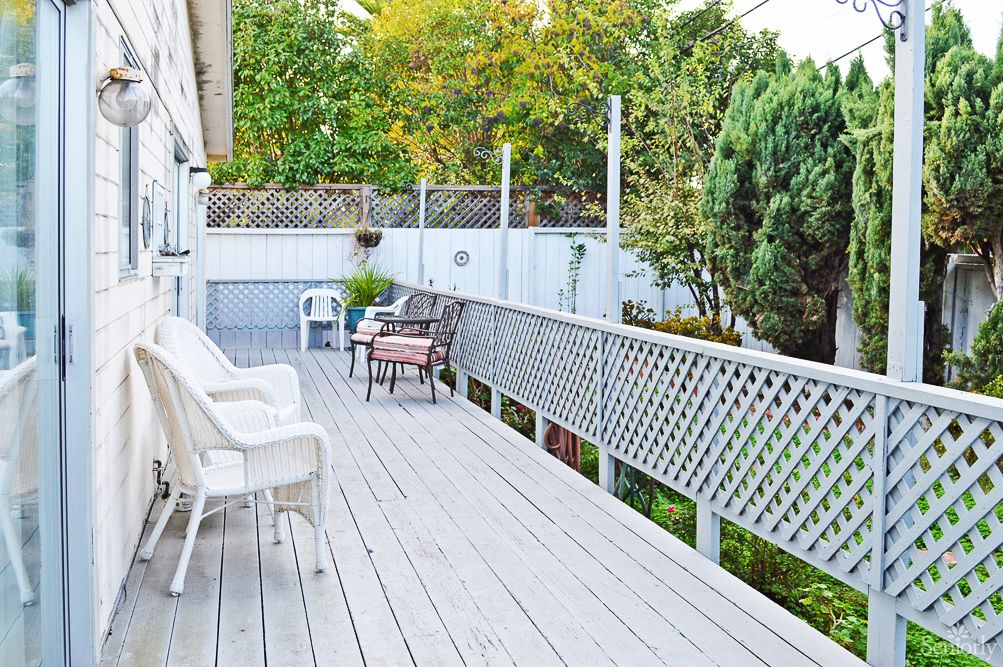 A spacious outdoor deck with chairs and a scenic view of surrounding trees.