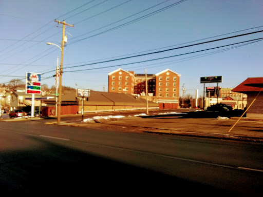 A view of an urban landscape featuring a multi-story building and a gas station along the road.