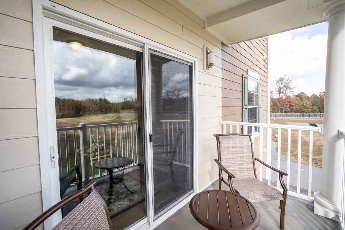 A cozy balcony with seating overlooks an outdoor area under overcast skies.