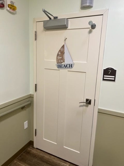 A door with a beach-themed sailboat sign and room number.