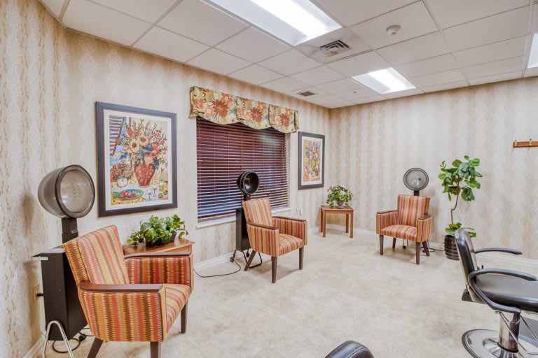 A cozy waiting room with striped chairs, decorative plants, and framed artwork on the walls.